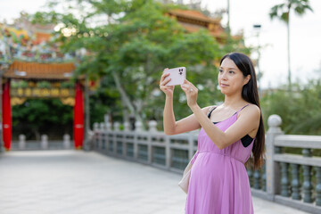 Poster - Asian pregnant use mobile phone to take photo at outdoor