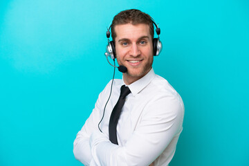 Wall Mural - Telemarketer caucasian man working with a headset isolated on blue background with arms crossed and looking forward