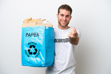 Wall Mural - Young caucasian man holding a recycling bag full of paper to recycle isolated on white background making money gesture