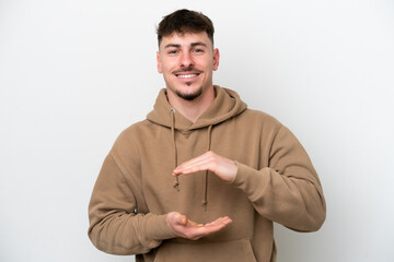 Wall Mural - Young caucasian handsome man isolated on white background holding copyspace imaginary on the palm to insert an ad