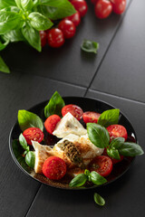 Wall Mural - Mozzarella with basil, cherry tomatoes and pesto sauce sprinkled with Mediterranean spices.