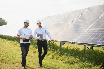 The solar farm, solar panel with two engineers walk to check the operation of the system, Alternative energy to conserve the world's energy