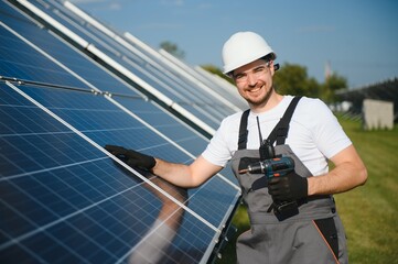 Poster - Man technician mounting photovoltaic solar moduls. Engineer in helmet installing solar panel system outdoors