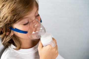 a beautiful child with a cough inhaler mask close-up, flu and cold season. space for text, space for copying, seasonal respiratory diseases, children's medicine