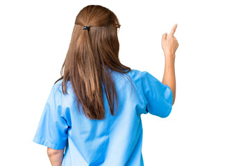 Wall Mural - Middle age nurse woman over isolated background pointing back with the index finger