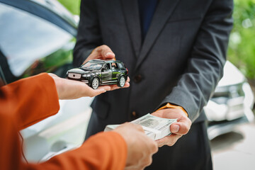 Wall Mural - Two Asian individuals discuss a car insurance claim with an agent in front of a damaged vehicle. They review documents, discuss the policy, and address the crash and repair costs.