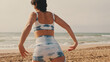 © Andrii Nekrasov - Close-up side view of a girl doing yoga on the beach, yoga class by the sea, back view
