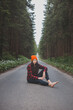 © Fauren - Charming brunette sitting on a path surrounded by wild nature, enjoying the feeling of freedom and fresh air. Lush greenery and tall trees, symbolizing adventure and tranquility in nature