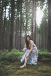 © Fauren - Pretty young brunette aged 20-25 is sitting in the forest in a colourful dress. Joy of clean air and the power of nature. Forest fairy. Feel beautiful and tender