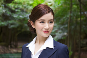 Businesswoman smiling woods. Woman in a blue suit, smiling, against a background of leafy green trees.