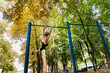 © Roman - A boy practicing outside doing tricks on the bar. Athletic teenage boy in the park outdoor workout session
