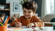 © Sittipol  - boy sitting at a table and drawing with colored pencils ,Happy child boy draws with colored pencils in white room studio