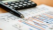 © Handz - Close-up of Pen on a Spreadsheet with Financial Charts and Calculator in the Background