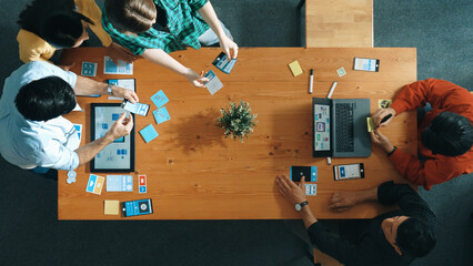 Programmer sharing Ux Ui design for mobile phone interface idea with software developer at meeting while designer writing idea at sticky notes. Start up team develop wireframe prototype. Convocation.