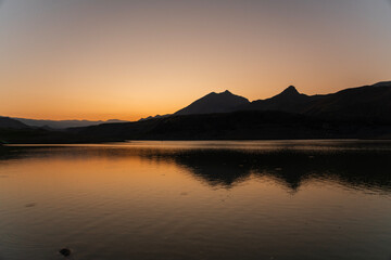 Wall Mural - bright orange sunrise over the lake and mountains.