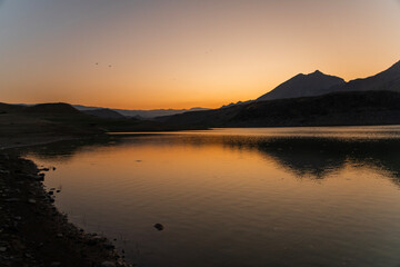 Wall Mural - bright orange sunrise over the lake and mountains.