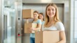 © Dream Vision - Three young women smiling in an elevator, holding cardboard boxes. Moving day concept.