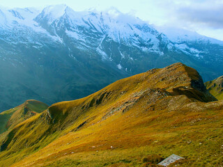 Wall Mural - mountainous landscape with verdant mountain slope in front of bare snow-capped mountain peaks in aut