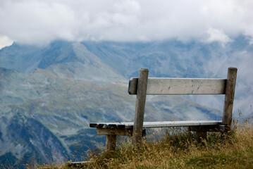Wall Mural - close-up of a wooden bench with a view of an amazing mountain landscape on a hazy day with gray clou
