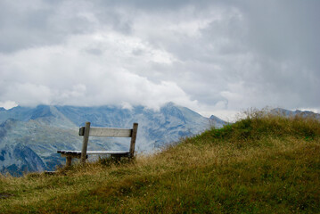 Wall Mural - close-up of a wooden bench with a view of an amazing mountain landscape on a hazy day with gray clou