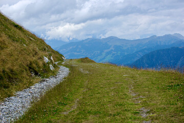 View of an amazing mountain landscape with a stony path on a hazy day with gray clouds and fog over the peaks in autumn in Austria.