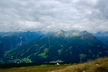 Wall Mural - view of an amazing mountain landscape with a village in the valley on a hazy day with gray clouds an