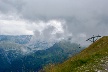 Wall Mural - view of an amazing mountain landscape with a gondola lift on a hazy day with gray clouds and fog ove