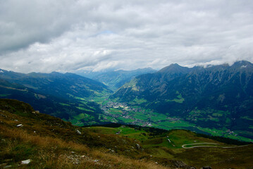 Wall Mural - view of an amazing mountain landscape with a village in the valley on a hazy day with gray clouds an