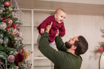 winter holidays and family concept - happy middle-aged father and baby daughter decorating christmas tree with ball