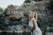 © qunica.com - Portrait of a woman in a white dress posing gracefully outdoors with a rocky natural background, conveying peace and elegance.