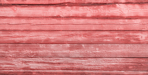 Texture of the old cracked wall made of wooden panels covered with thick layer of pastel pink paint as a background