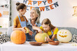© Maria Vitkovska - Grandmother and granddaughters carving pumpkins for halloween party, creative, hand made concept
