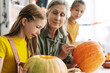 © Maria Vitkovska - Grandmother helping little girls carving pumpkins for halloween celebration