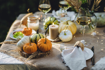 Fall still-life. Orange pumpkins, dry flowers and candles on linen tablecloth. Dinner table outdoors in the garden. Cozy autumn concept., simple handmade decoration, countryside style