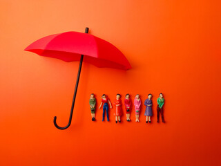 Miniature people women protected by red umbrella