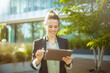 © Alliance - happy woman worker near office building using digital tablet