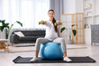 © New Africa - Beautiful pregnant woman with dumbbells doing exercises on fitball at home