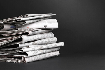 Canvas Print - Stack of newspapers in different languages on black background. Space for text