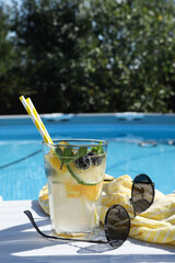 Poster - Tasty cocktail in glass and sunglasses near swimming pool outdoors