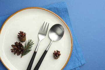 Sticker - Beautiful Christmas setting with plate, cutlery and cones on blue table, top view