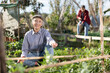 © JackF - Positive old woman in shirt and jeans weeding vegetable beds with chopper while working in garden during daytime in spring