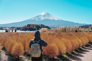 Wall Mural - Woman tourist with Fuji Mountain at Lake Kawaguchi, happy Traveler sightseeing Mount Fuji in Fujikawaguchiko, Yamanashi, Japan. Landmark for tourists attraction. Japan Travel, Destination and Vacation