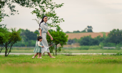 Wall Mural - mother walking with her crying toddler baby girl on grass field in park