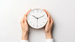 © PTC_KICKCAT - Close-up of hands holding a minimalistic round wall clock on white background, depicting time management and punctuality.