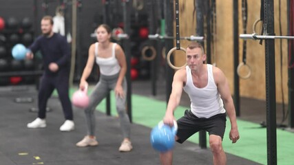 Wall Mural - Determined young guy working out with kettlebell in well-equipped gym during training session 