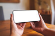 © Farknot Architect - Mockup image of a woman holding and using mobile phone with blank desktop at home