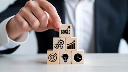 Poster - Hand arranging wooden blocks with vital business strategy icons ascending like steps, symbolizing growth and planning.