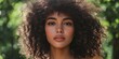 © Iryna - A woman with curly hair is smiling and looking at the camera. She has a light makeup on her face