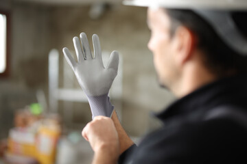 Construction worker putting protection gloves