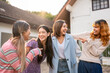 © Kawee - Group of women friends standing together outdoors in front of a house.